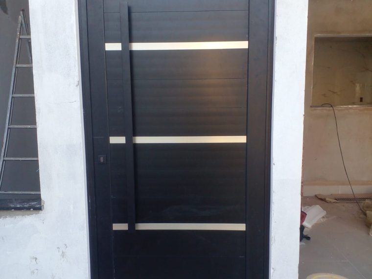 Porta pivotante de alumínio preto com frisos em inox
